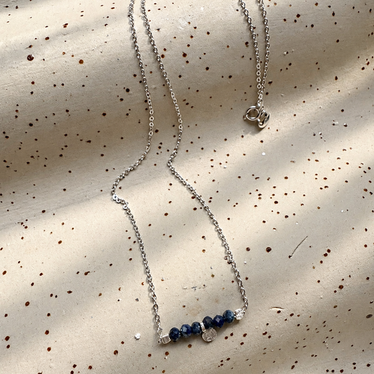 Minimalistische Halskette aus 925er Sterlingsilber mit Lapislazuli und gehämmertem Silberanhänger auf beigem Keramik